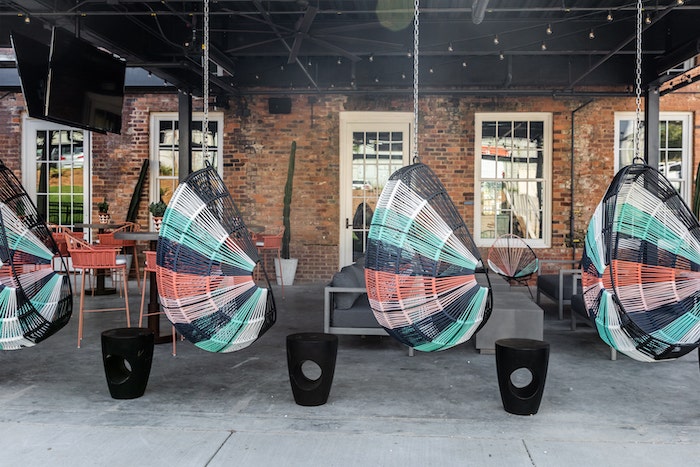 Symmetrical chair swings with stripes of blue and coral provide bursts of color to the outdoor lounge area.