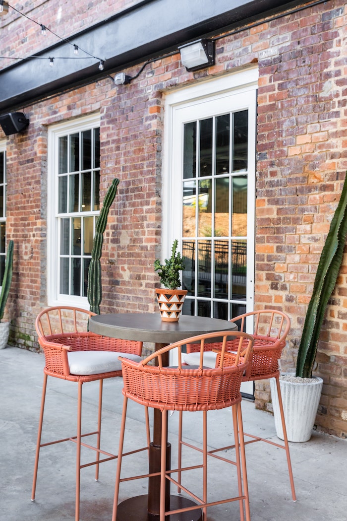 Crisp white Sunbrella cushions adorn the coral high top dining chairs in the outdoor dining area at El Thrifty.