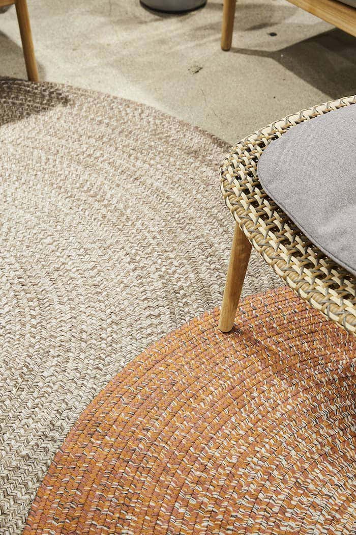 Layered rugs in Gloster’s showroom display provide dimension and texture to make an outdoor area feel like a defined space.