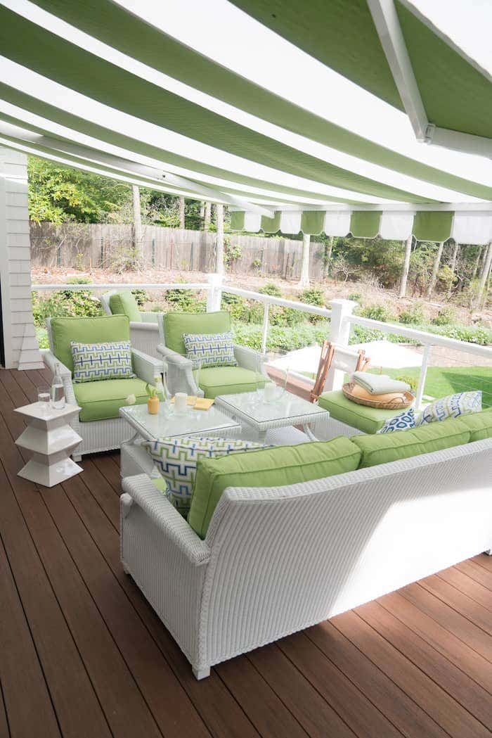 Upstairs patio with outdoor wicker furniture covered by a striped Sunbrella retractable awning