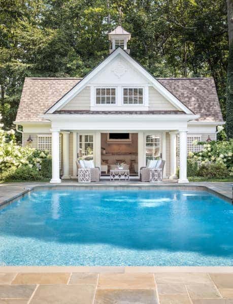 A stunning patio equips this Long Island home with a comfortable transitional space and a beautiful view of the house’s pool.