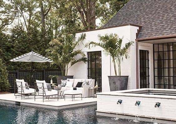 Summer Classics black and white Sunbrella upholstered pieces enhance the natural landscape in this backyard patio space. Photo courtesy of Summer Classics