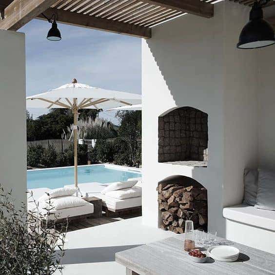 AM Designs incorporated crisp white Sunbrella fabrics to cover this poolside lounge, contrasting the black light fixtures and natural wood. Photo courtesy of AM Designs