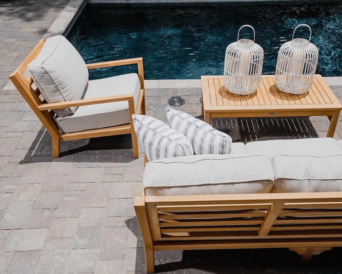 Teak wood outdoor patio furniture set by the pool with neutral Sunbrella outdoor upholstery fabric cushions and pillows