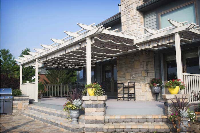 The elegant look of the Trex Pergola from ShadeTree paired with neutral Sunbrella shade keeps this home’s patio cool all year round.