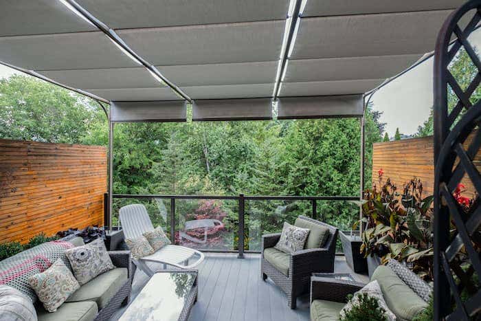 A second story patio outfitted with a bungalow shade structure from ShadeTree clad in a slate grey Sunbrella fabric creates the perfect perch for morning coffee or an afternoon glass of wine.