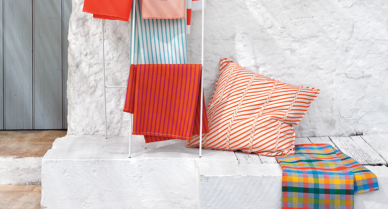 hanging fabric and orange striped pillow against white outdoor wall