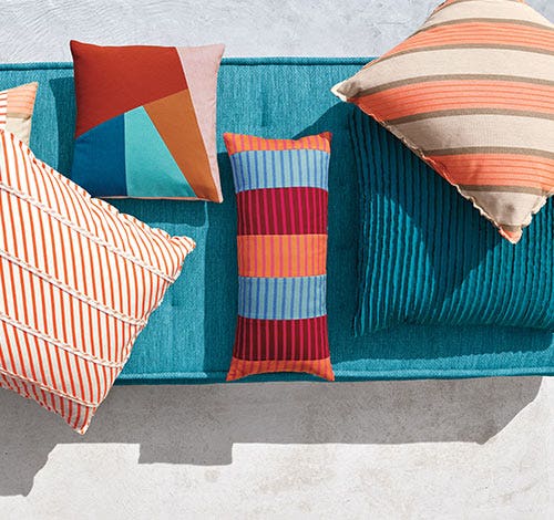 Topdown view of assortment of bright blue and orange outdoor cushions