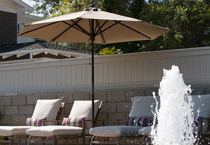 Beige umbrella over grey pool chairs